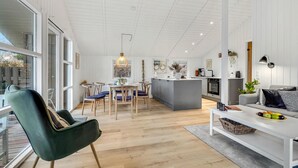 Tilava olohuone, jossa on ruokapöytä, sohva ja taustalla keittiö.