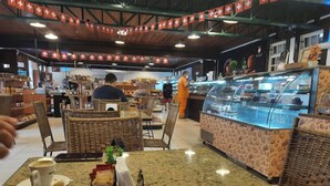 A café with wicker furniture, a coffee bar, and a display case with pastries.