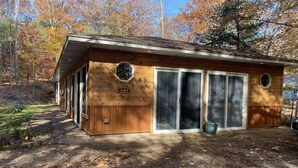 A wooden cabin with a number 8778, large sliding glass doors, and a small porch area. - Sweet Retreat West..sandy ORV's and memories made here (Mears)
