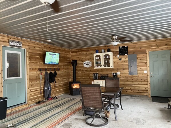 A cozy cabin interior with a wooden interior, a coffee bar, a fireplace, and a television mounted on the wall.