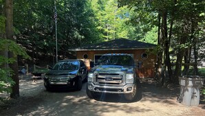 Two parked trucks in front of a cabin with a wooden roof and a flagpole. - Sweet Retreat West..sandy ORV's and memories made here (Mears)