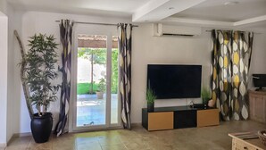 A living room with a large TV, a potted plant, and a sliding glass door leading to a patio. - 5 bedroom lovely home in Rians (Rians)