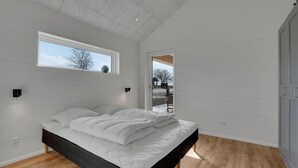 A bedroom with a large bed, a skylight, a sliding door to a balcony, and a view of the outside. - Stunning home in Samsø with sauna (Samsø)