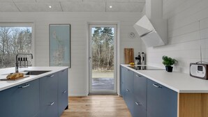 A modern kitchen with two islands, a large window, and a view of trees outside. - Stunning home in Samsø with sauna (Samsø)