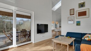 A modern living room with a TV, wooden furniture, and artwork on the walls. - Stunning home in Samsø with sauna (Samsø)
