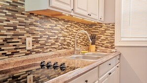 A kitchen with white cabinets, a tiled backsplash, a stainless steel sink, and a window with blinds. - Cozy apartment 1st 10min Walk Downtown | City View (Providence)