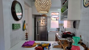 Una cocina con refrigerador, lámpara colgante y ventana.