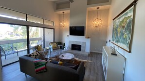 Un salon spacieux doté d’une cheminée, de grandes fenêtres et d’un ventilateur de plafond.
