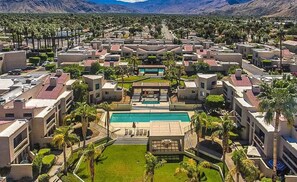 Ein Resort mit mehreren Gebäuden, einem zentralen Pool und Palmen.