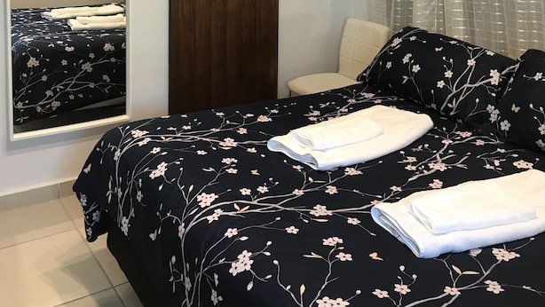 Une chambre à coucher comprenant un lit, une chaise, une armoire, un appareil de climatisation et une fenêtre avec des rideaux.