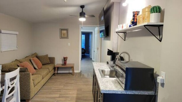 Een ruimtelijk ingerichte leefruimte met kitchenette, eethoek en zithoek.