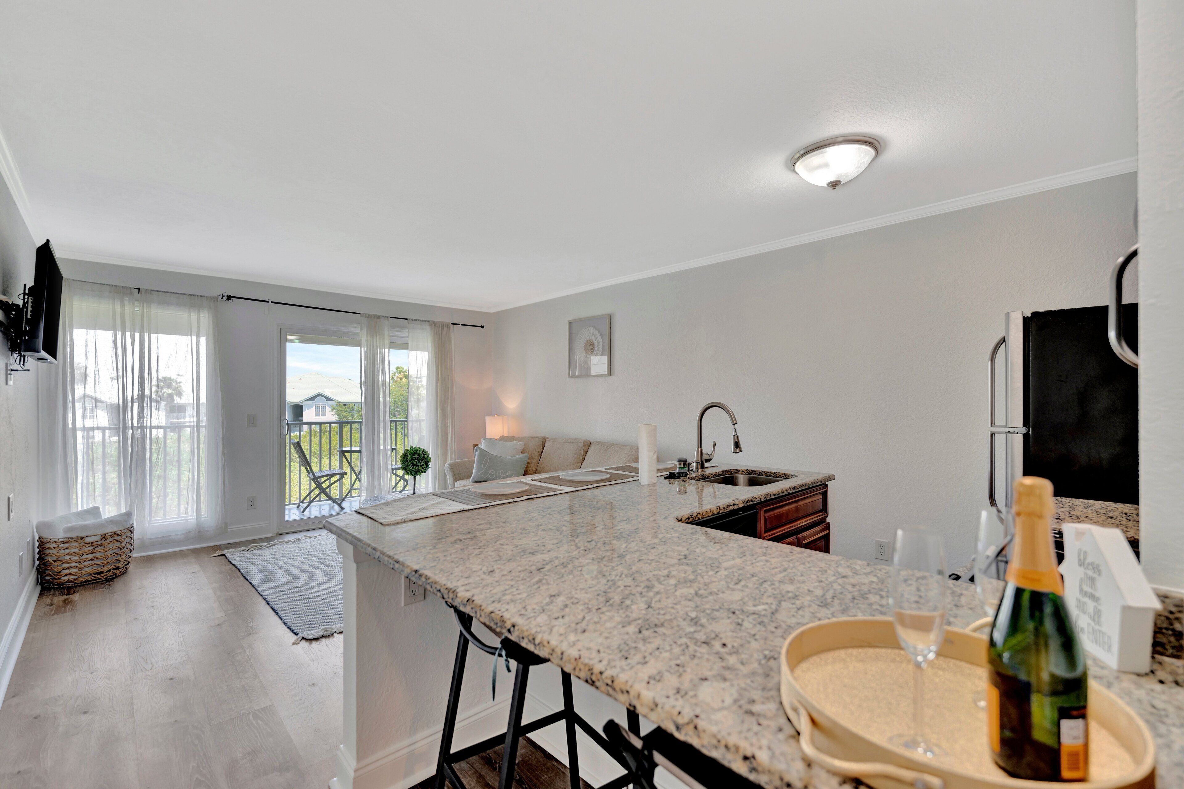 A modern kitchen with a granite countertop, a built-in sink, and a large window overlooking a balcony.