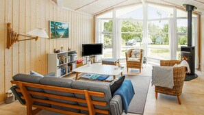 A cozy living room with a sofa, a television, a bookshelf, and a fireplace. - 3 bedroom beautiful home in Samsø (Samsø)