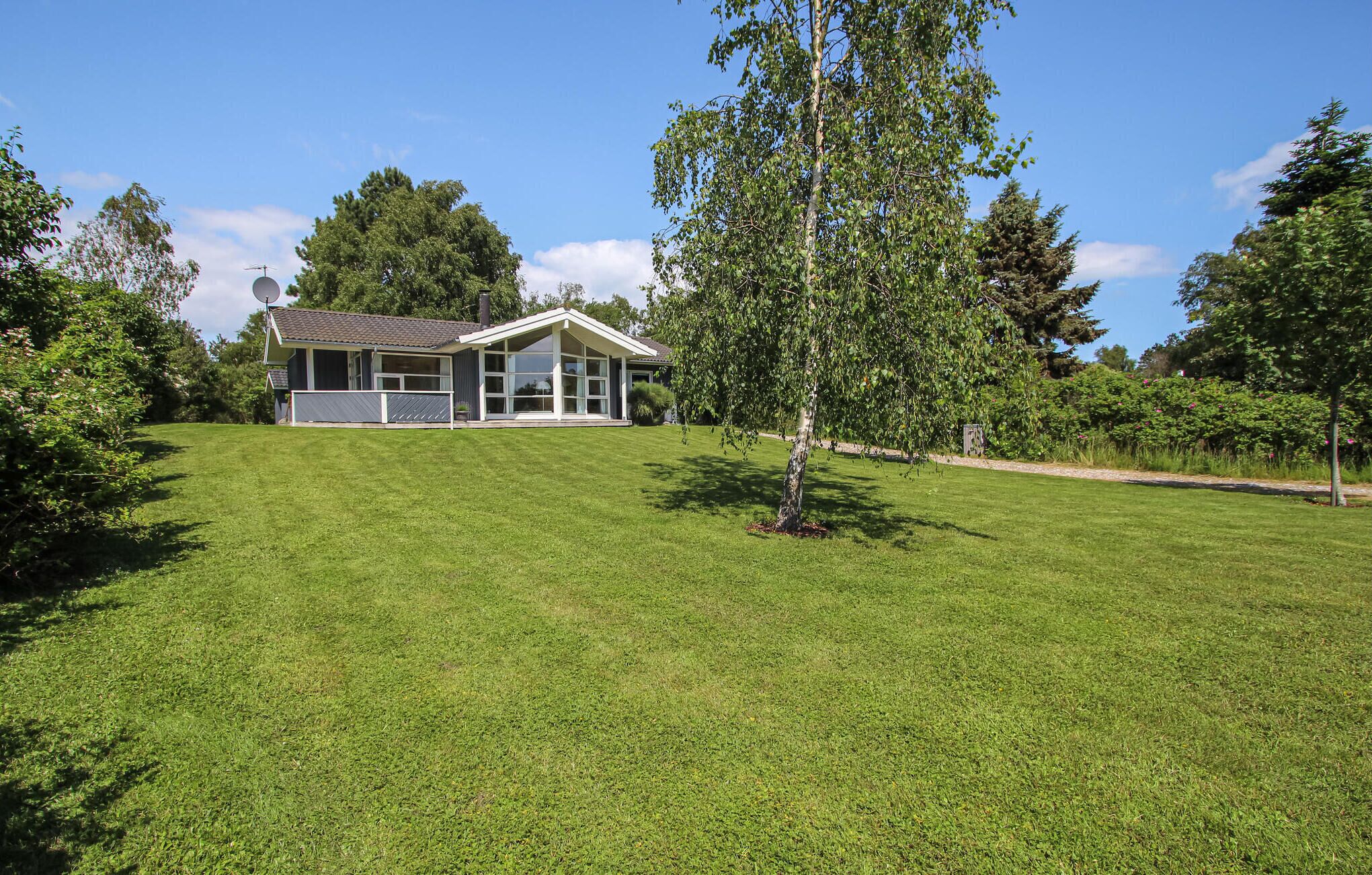 A modern house with a large lawn, a satellite dish, and a well-maintained garden.