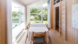 A dining area with a table set for six, wooden chairs, and large windows offering a view of the outdoors. - 3 bedroom beautiful home in Samsø (Samsø)