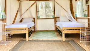 Una habitación acogedora con dos camas de madera, un tapete verde estampado y una ventana con cortinas.