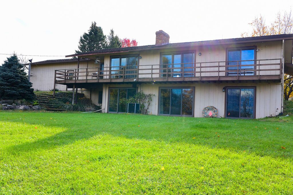 A two-story house with a balcony, large windows, and a grassy yard.