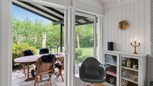 A room with a wooden table and chairs, a black chair, a white cabinet with glass doors, and a wreath on the wall. - Nice home in Tisvildeleje with WiFi (Tisvildeleje)