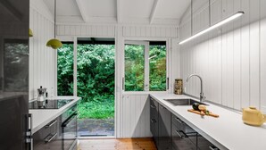 A modern kitchen with white cabinetry, a large window, and a view of greenery outside. - Nice home in Tisvildeleje with WiFi (Tisvildeleje)