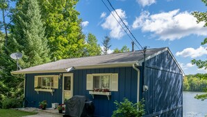 Una piccola casa a un piano con facciata blu scuro, una griglia coperta e un'antenna parabolica.
