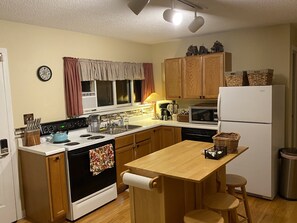 Enjoy meals in the kitchen with a stove, sink, microwave, and refrigerator. Dine at the wooden table with two stools.