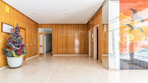 A hallway with wooden paneling, a Christmas tree, and a tiled wall with a bird mural. - Gorgeous apartment in Estepona (Estepona)