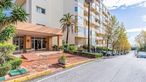 A multi-story hotel with a modern design, featuring a prominent entrance with a glass door and a sign indicating the name and room count. - Gorgeous apartment in Estepona (Estepona)