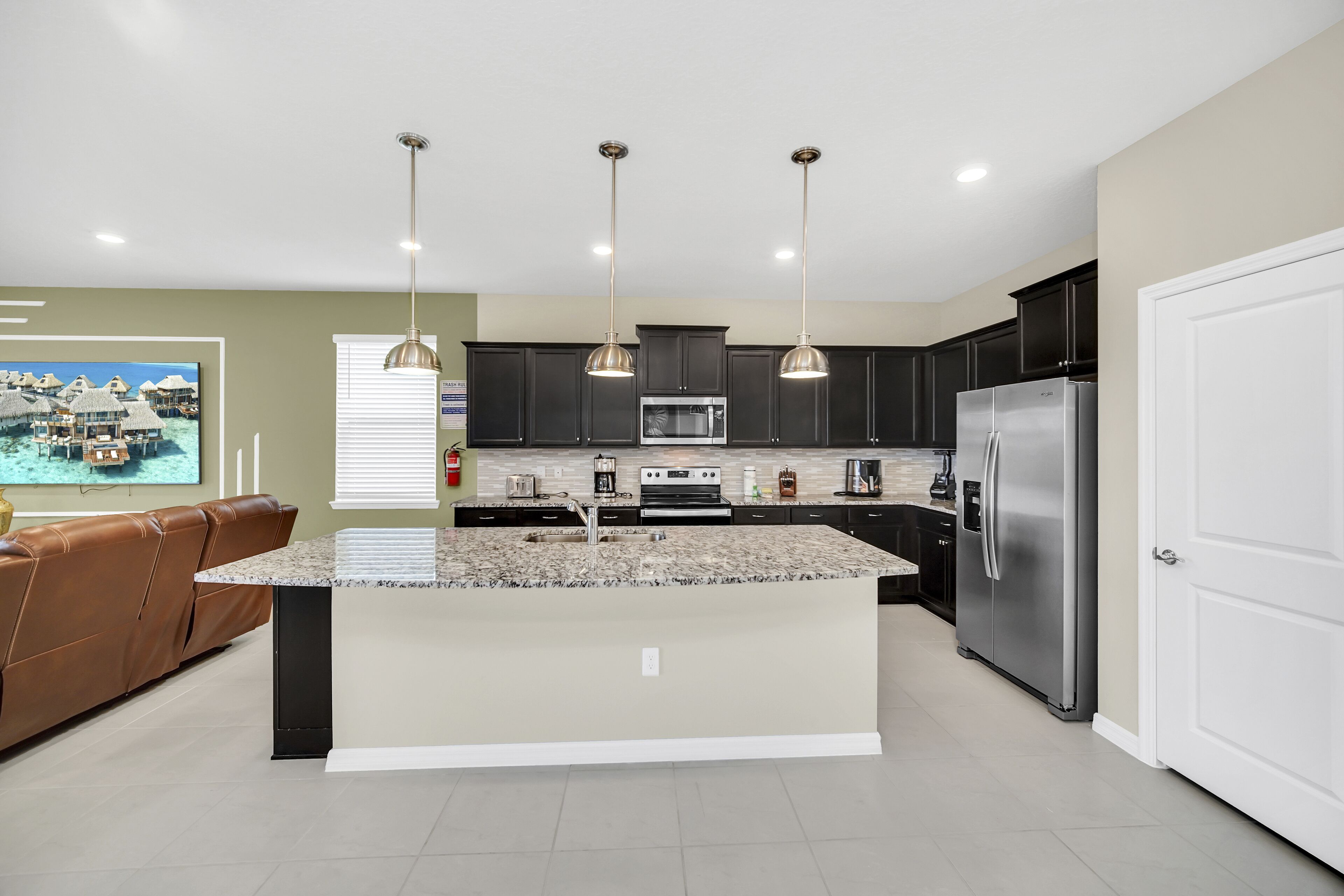 A modern kitchen with dark cabinets, stainless steel appliances, and a central island.