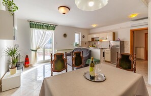 Enjoy casual dining and relaxation in this open-plan living area with a dining table for two, kitchenette, and comfortable seating.