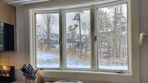 A kitchen with a large window, a wooden cutting board, and a knife block. - Red Bear Inn- 6.5 Baths! Grill, Pool, Central (Killington)