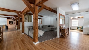 A spacious room with exposed wooden beams, a sectional sofa, and a large window. - Red Bear Inn- 6.5 Baths! Grill, Pool, Central (Killington)