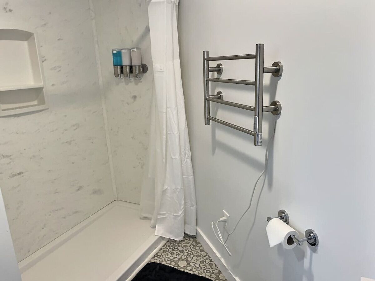 Een badkamer met een douche, een toiletrolhouder en een handdoekrek.