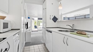 A modern kitchen with white cabinets, a built-in microwave, a sink, and a window overlooking a garden. - Lovely home in Samsø with WiFi (Samsø)