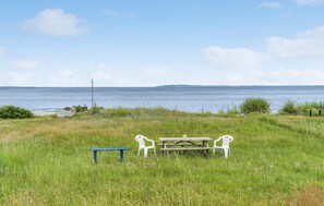 Une table de pique-nique avec des bancs et un banc bleu, le tout situé dans un espace verdoyant avec vue sur la mer.
