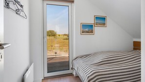 Een slaapkamer met een bed, een schuifglasdeur naar een balkon en twee ingelijste foto's aan de muur.
