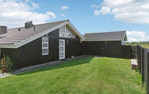 A single-story building with a sloped roof, a small front porch, and a fenced backyard. - Beautiful home in Hjørring with WiFi (Hjørring)