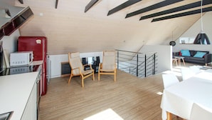 A compact, modern loft apartment with a wooden floor, a kitchenette with a red refrigerator, two wooden chairs, a dining table, and a black metal staircase. - Beautiful home in Samsø with WiFi (Samsø)