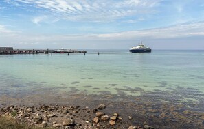 Un quai pour les traversiers offrant une vue dégagée sur l’eau et sur un grand navire au loin.