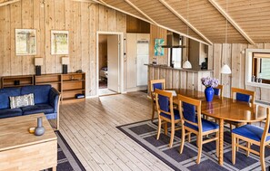 Un intérieur en bois comprenant un canapé, une table à manger, des chaises et un coin cuisine.