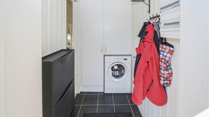 A laundry room with a front-loading washing machine, a drying rack, and a vented cabinet.