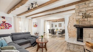 A living room with a grey sofa, a round wooden coffee table, and a stone fireplace. - Awesome home in Modrusani (Modrusani)
