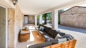 A covered outdoor seating area with a sofa, a wooden bench, and a table with fruits. - Awesome home in Modrusani (Modrusani)