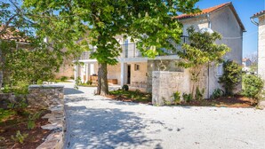 A two-story building with a stone facade, a balcony, and a gravel driveway. - Awesome home in Modrusani (Modrusani)