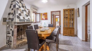A dining area with a stone fireplace, wooden dining table, and chairs. - Spacious 5-bedroom Villa with pool and barbecue (Can Picafort)