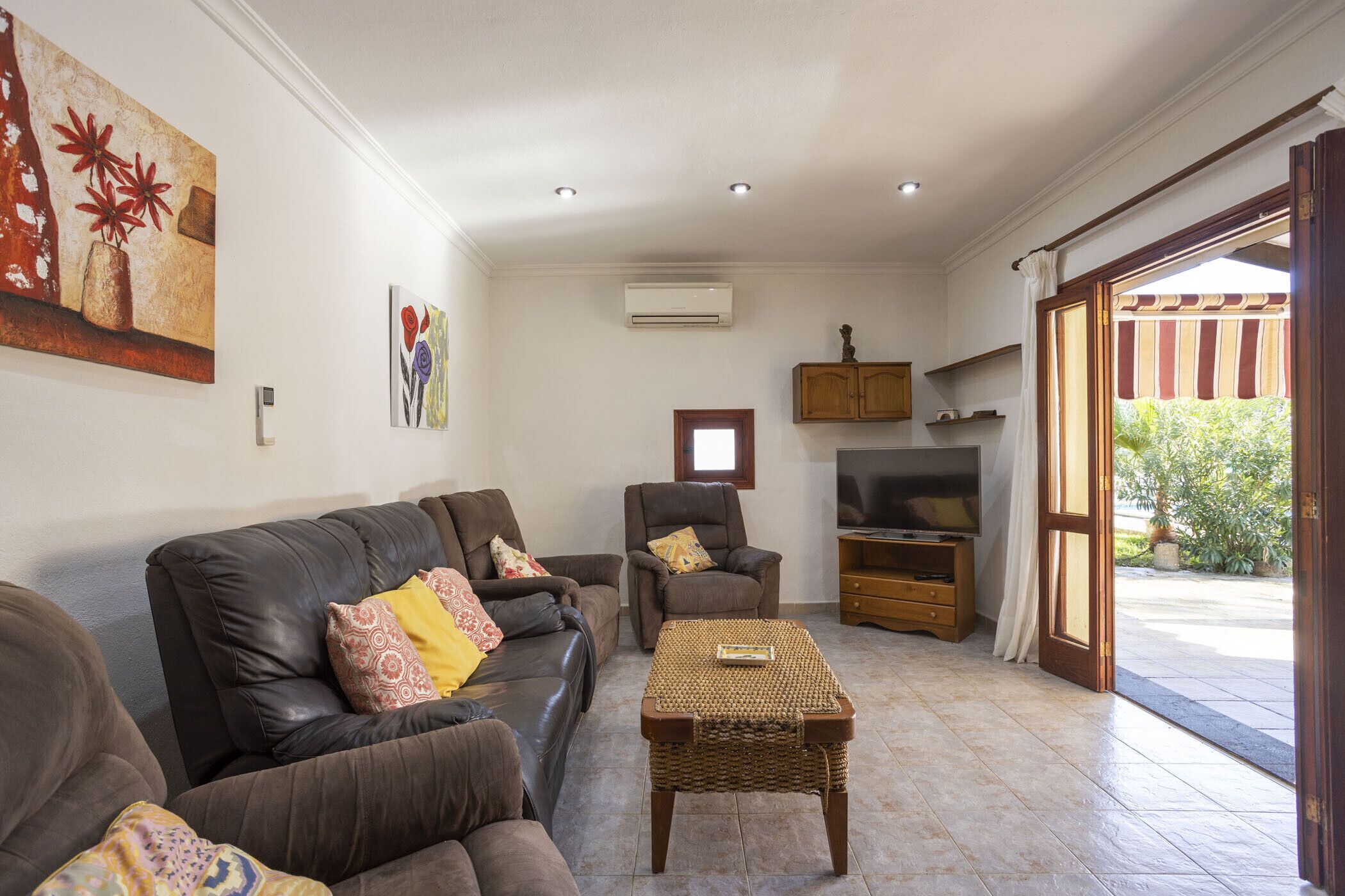 A living room with a sofa, armchairs, a TV, and a small table.