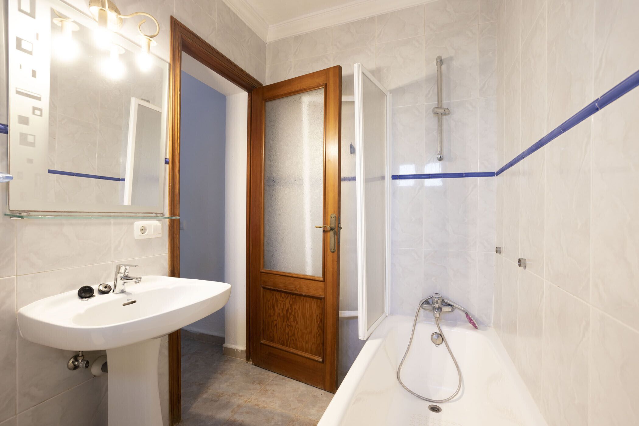 A bathroom with a white sink, a wooden door, and a bathtub.
