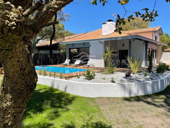 A modern house with a swimming pool, surrounded by a landscaped garden and a large tree. - Villa LAC (SEIGNOSSE)