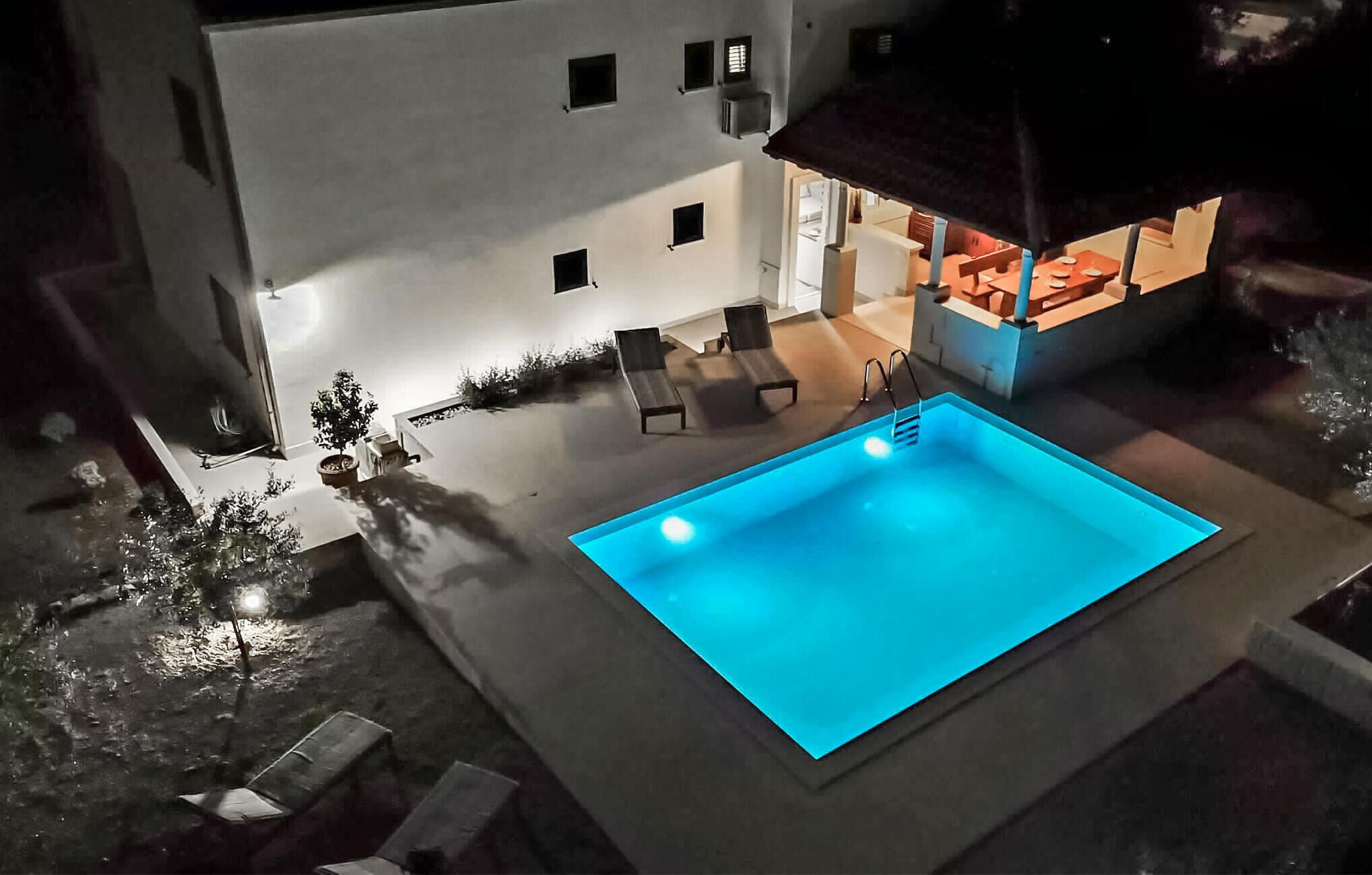 A modern building with a swimming pool, outdoor seating, and a covered area.