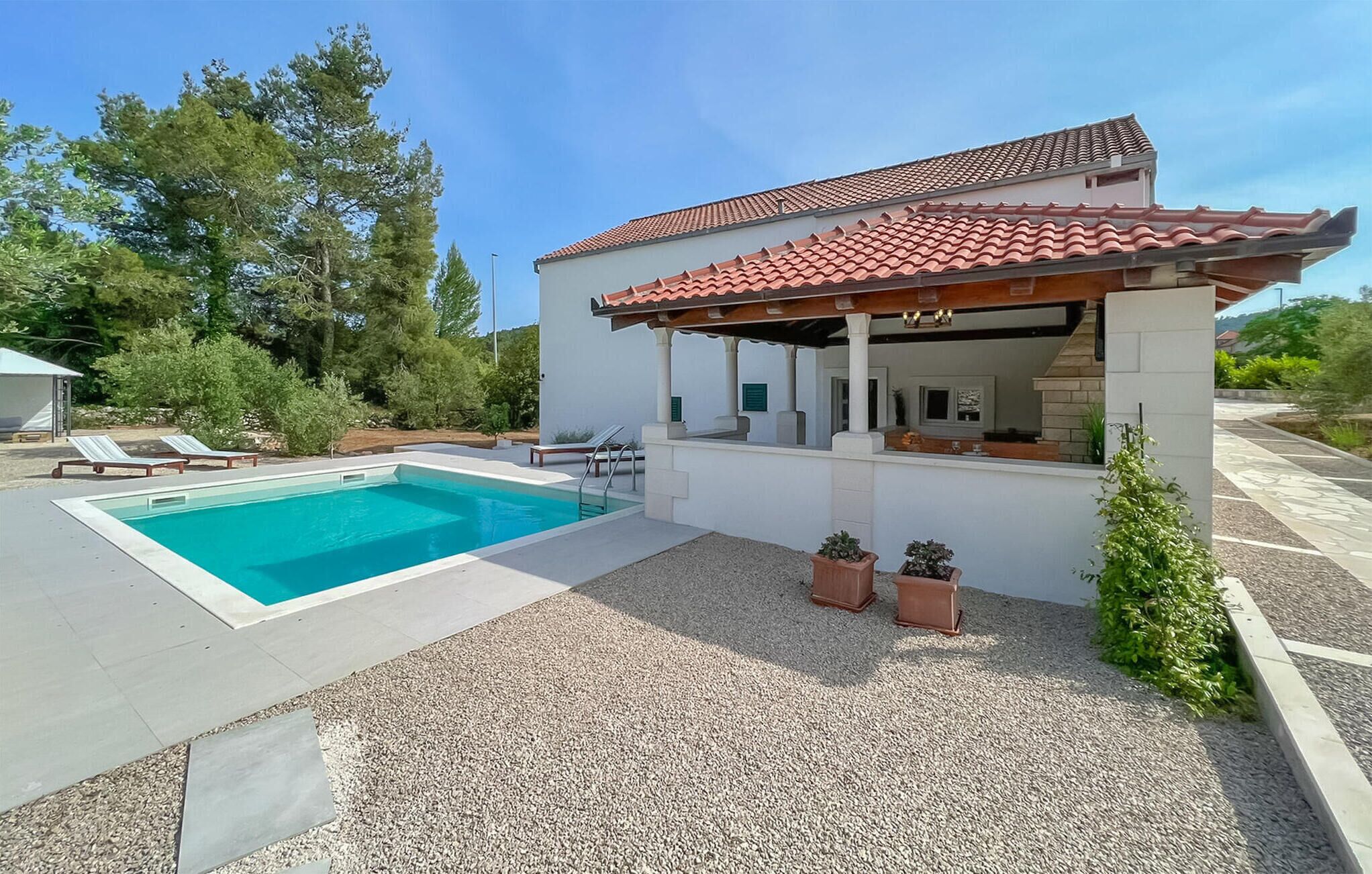 A modern house with a swimming pool, outdoor seating, and a covered patio.