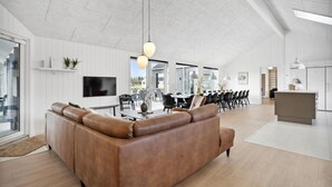 Ein modernes Wohnzimmer mit Ledersofa, Essbereich und Küche.